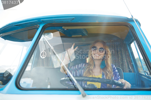 Image of smiling young hippie woman driving minivan car