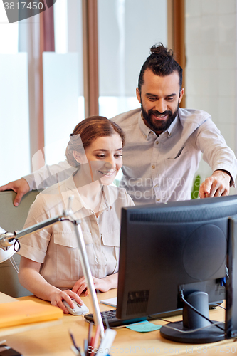 Image of happy creative team with computer in office