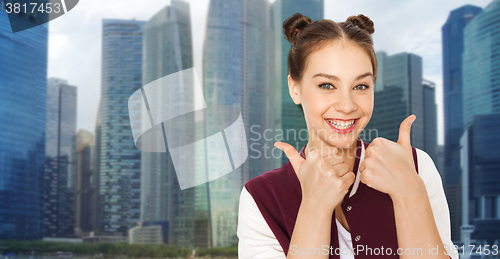 Image of happy teenage girl showing thumbs up over city