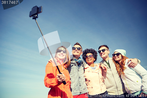 Image of smiling friends taking selfie with smartphone