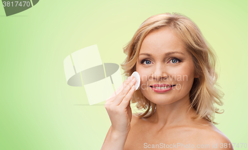 Image of happy woman cleaning face with cotton pad