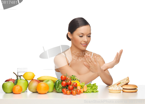 Image of woman with fruits rejecting hamburger