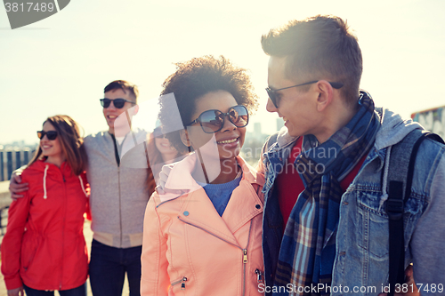 Image of happy teenage friends in shades talking on street