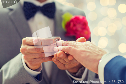 Image of close up of male gay couple hands and wedding ring