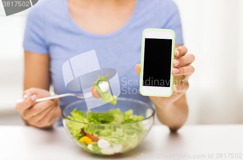 Image of close up of woman with smartphone eating salad