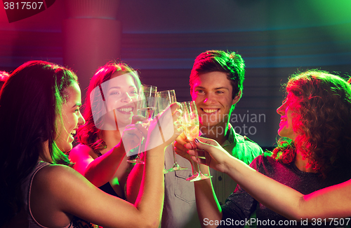 Image of smiling friends with glasses of champagne in club