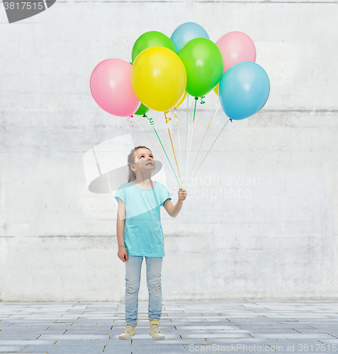 Image of girl looking up with bunch of helium balloons