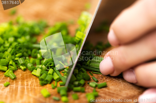 Image of close up of woman chopping green onion with knife