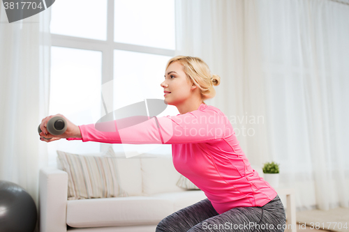 Image of smiling woman with dumbbells exercising at home