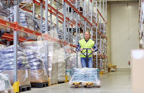 Image of man carrying loader with goods at warehouse