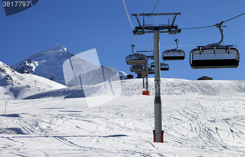 Image of Chair lift in snowy mountains at nice sunny day