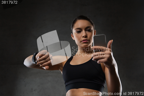 Image of woman with heart-rate watch and smartphone in gym