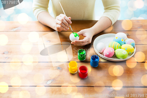 Image of close up of woman hands coloring easter eggs