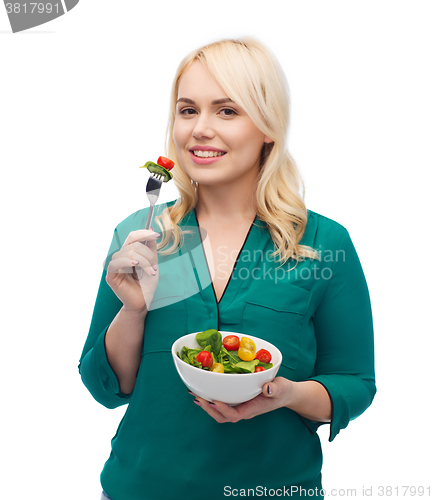 Image of smiling young woman eating vegetable salad