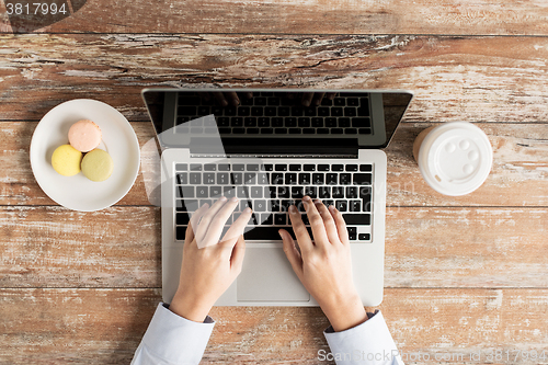 Image of close up of female hands with laptop and coffee