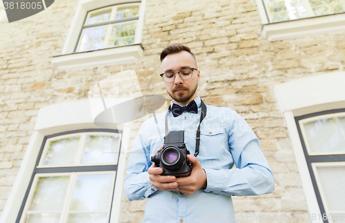 Image of happy young hipster man with film camera in city