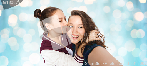 Image of happy teenage girls taking selfie and kissing