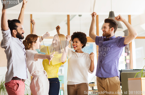 Image of happy creative team celebrating victory in office