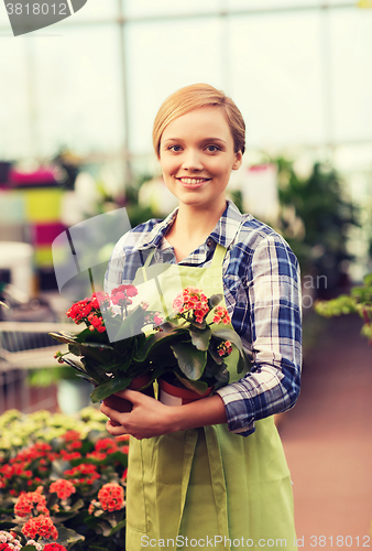 Image of happy woman holding flowers in greenhouse