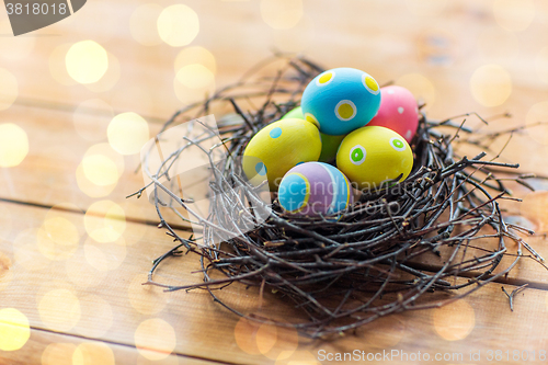 Image of close up of colored easter eggs in nest on wood