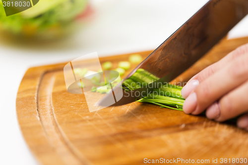 Image of close up of woman chopping green onion with knife