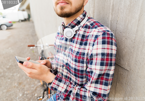 Image of hipster man in earphones with smartphone and bike