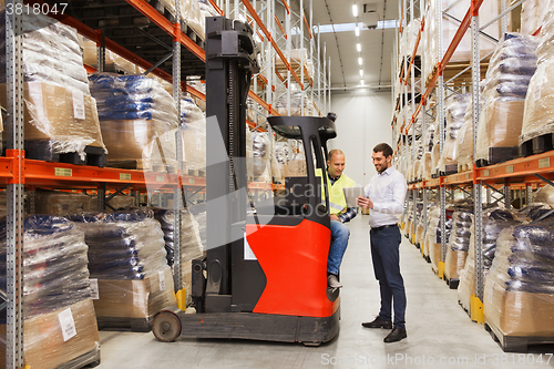 Image of men with tablet pc and forklift at warehouse