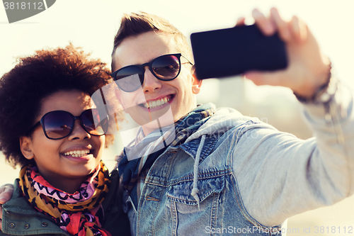 Image of happy teenage friends in shades taking selfie