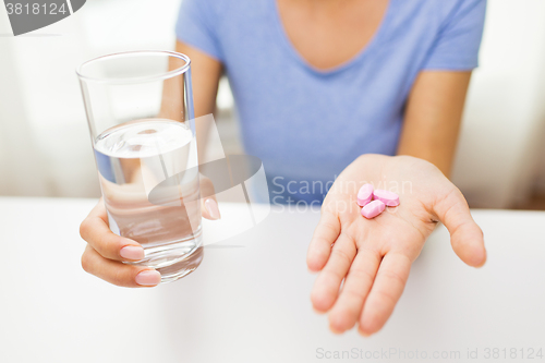 Image of close up of woman hands with pills and water