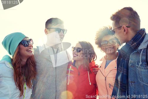 Image of happy teenage friends in shades talking on street