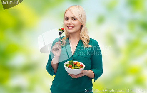 Image of smiling young woman eating vegetable salad