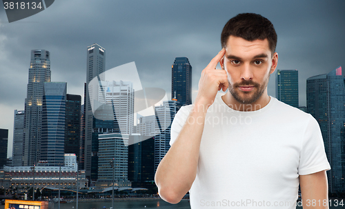 Image of man with finger at temple over singapore city