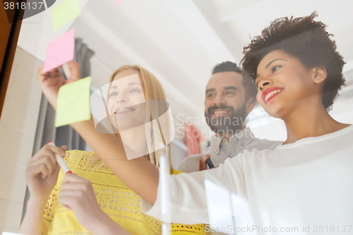 Image of happy creative team writing on stickers at office