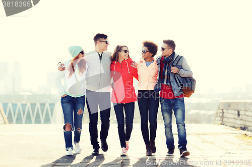 Image of happy teenage friends walking along city street