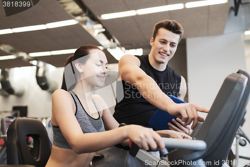 Image of happy woman with trainer on exercise bike in gym