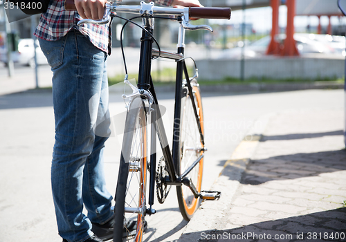 Image of close up of man and fixed gear bike on city street