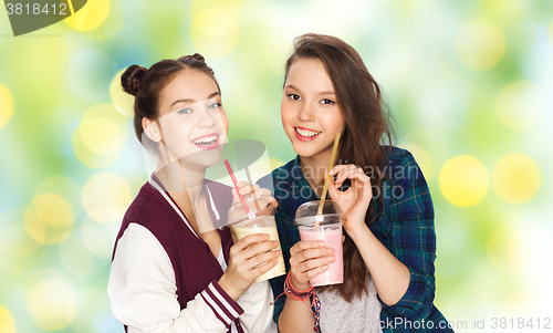 Image of happy pretty teenage girls drinking milk shakes