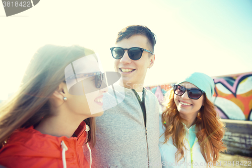 Image of happy teenage friends in shades talking on street