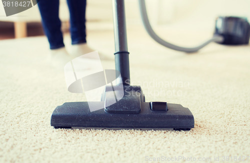 Image of close up of woman legs with vacuum cleaner at home