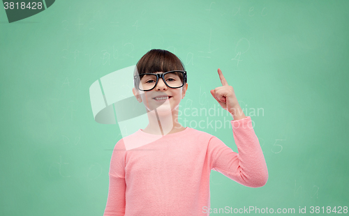 Image of happy little girl in eyeglasses pointing finger up