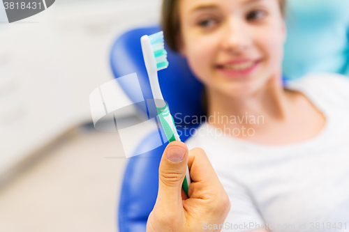 Image of close up of dentist hand with toothbrush and girl