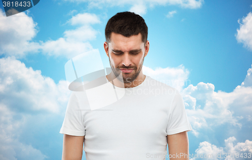 Image of unhappy young man over blue sky background