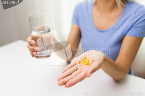 Image of close up of woman hands with capsules and water