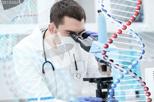 Image of young scientist looking to microscope in lab