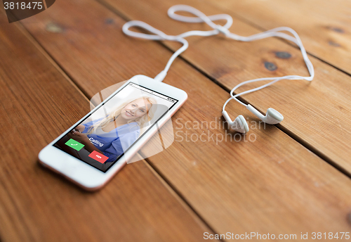 Image of close up of smartphone and earphones on wood