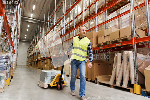 Image of man carrying loader with goods at warehouse