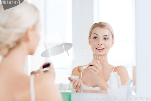 Image of woman with makeup brush and powder at bathroom