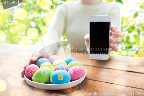 Image of close up of woman with easter eggs and smartphone