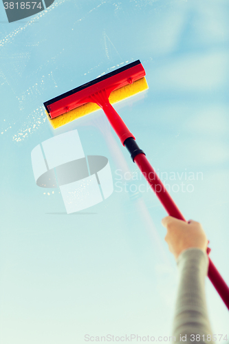 Image of close up of hand cleaning window with sponge