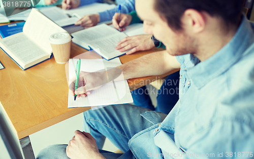 Image of happy students writing to notebooks in library